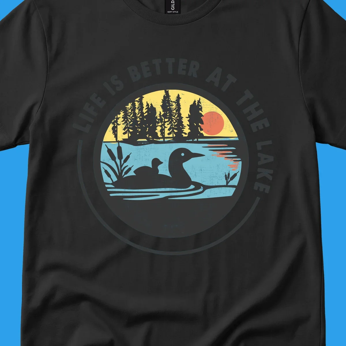 Circular lake scene with loons and trees, text "Life Is Better At The Lake".