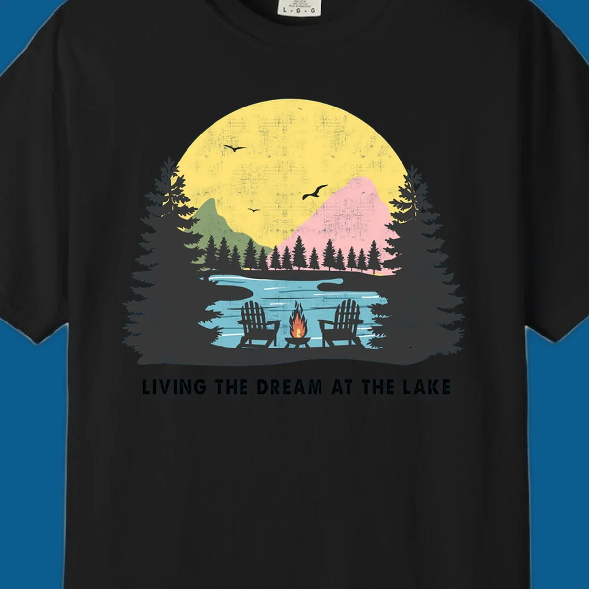 Lake life dream scene with Adirondack chairs, campfire, and sunset over mountains. Text: LIVING THE DREAM AT THE LAKE