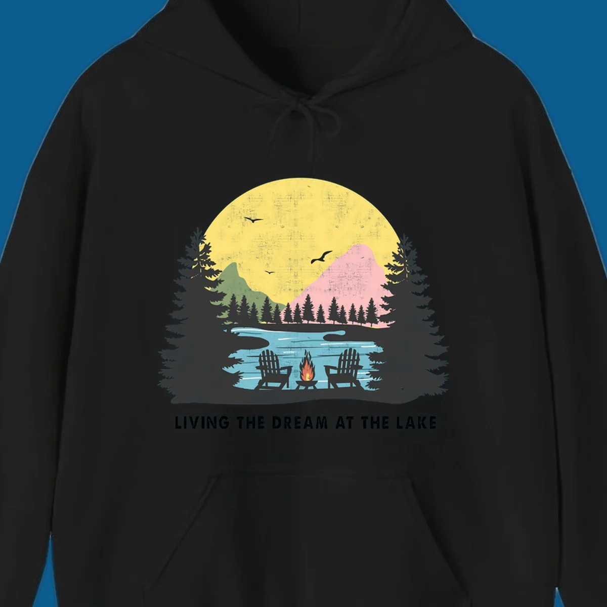 Lake life dream scene with Adirondack chairs, campfire, and sunset over mountains. Text: LIVING THE DREAM AT THE LAKE
