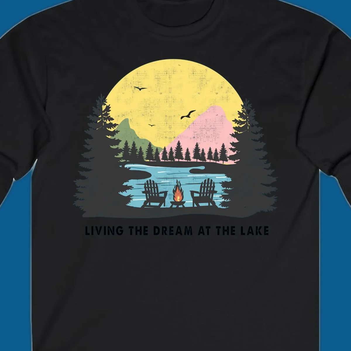 Lake life dream scene with Adirondack chairs, campfire, and sunset over mountains. Text: LIVING THE DREAM AT THE LAKE