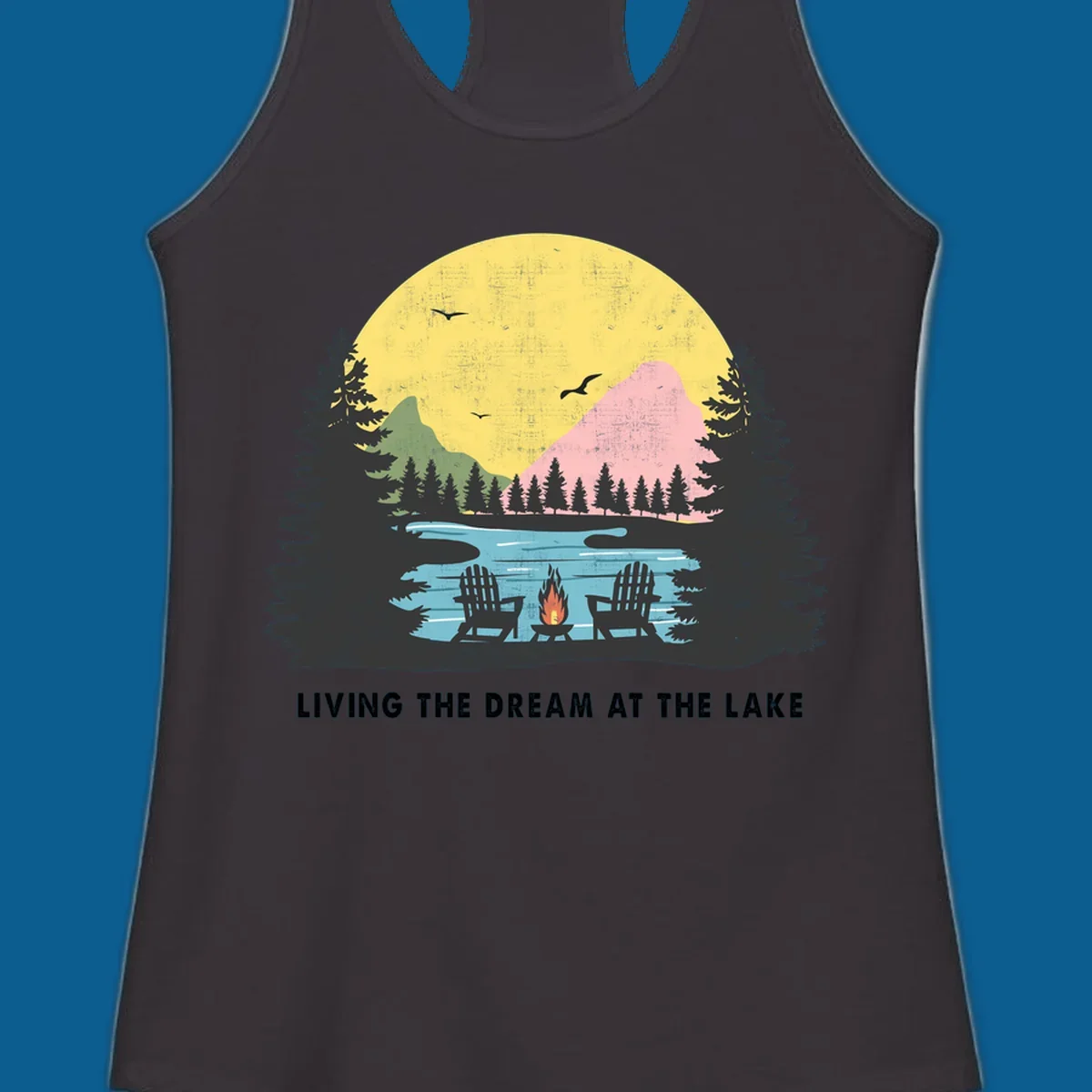 Lake life dream scene with Adirondack chairs, campfire, and sunset over mountains. Text: LIVING THE DREAM AT THE LAKE