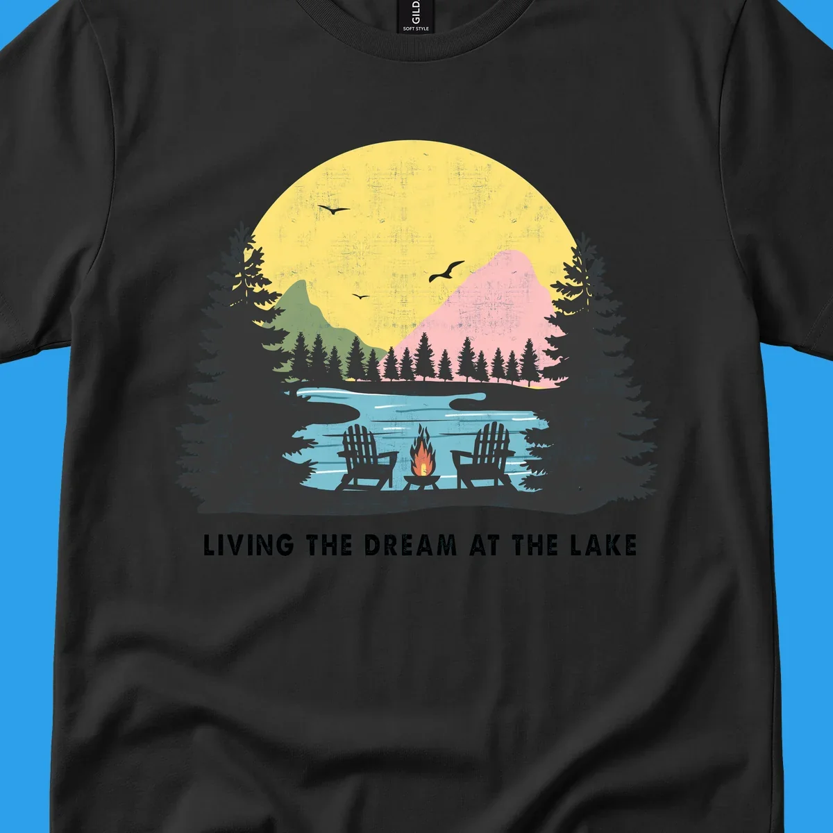 Lake life dream scene with Adirondack chairs, campfire, and sunset over mountains. Text: LIVING THE DREAM AT THE LAKE