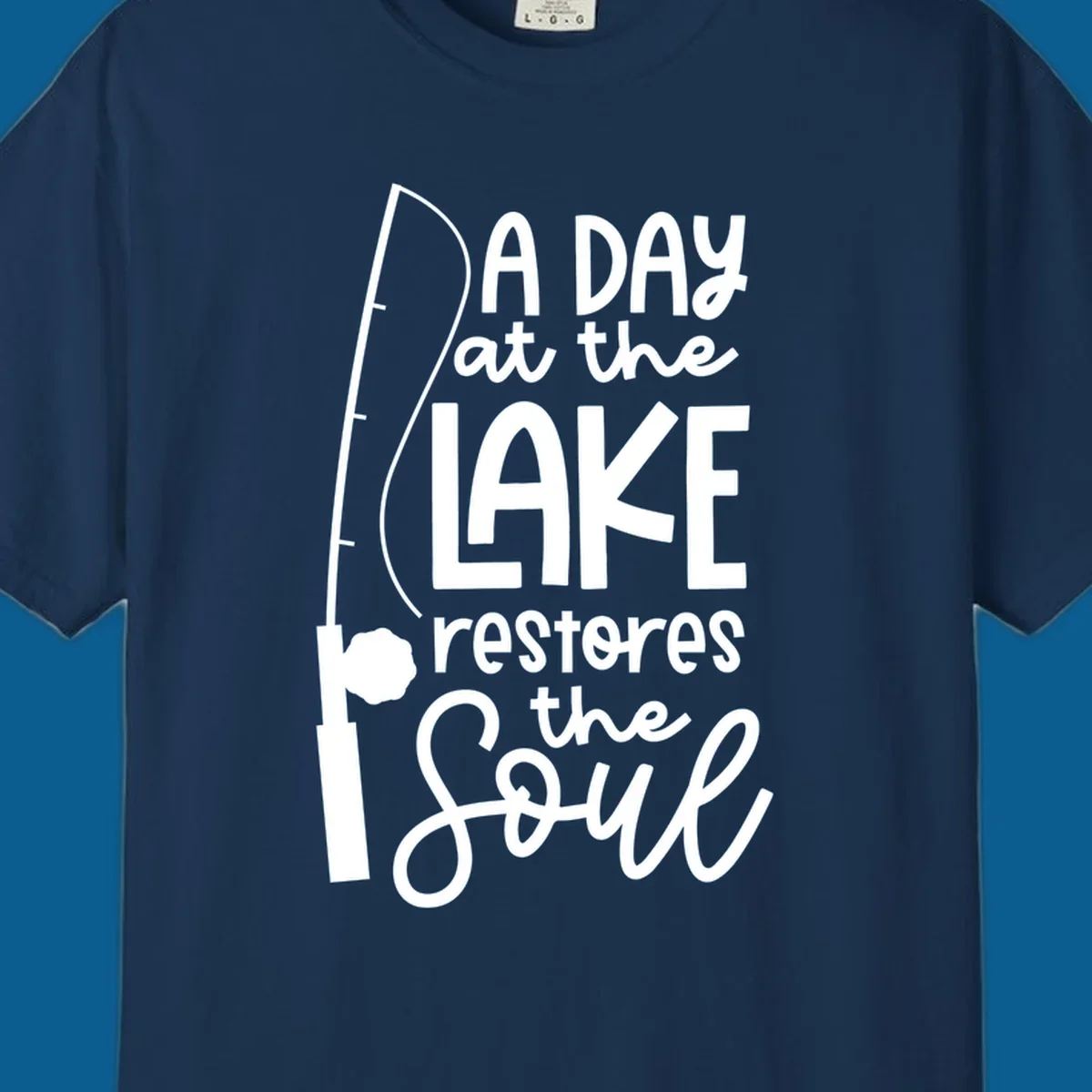 Fishing pole with text "A Day at the Lake Restores the Soul", lake-life concept.