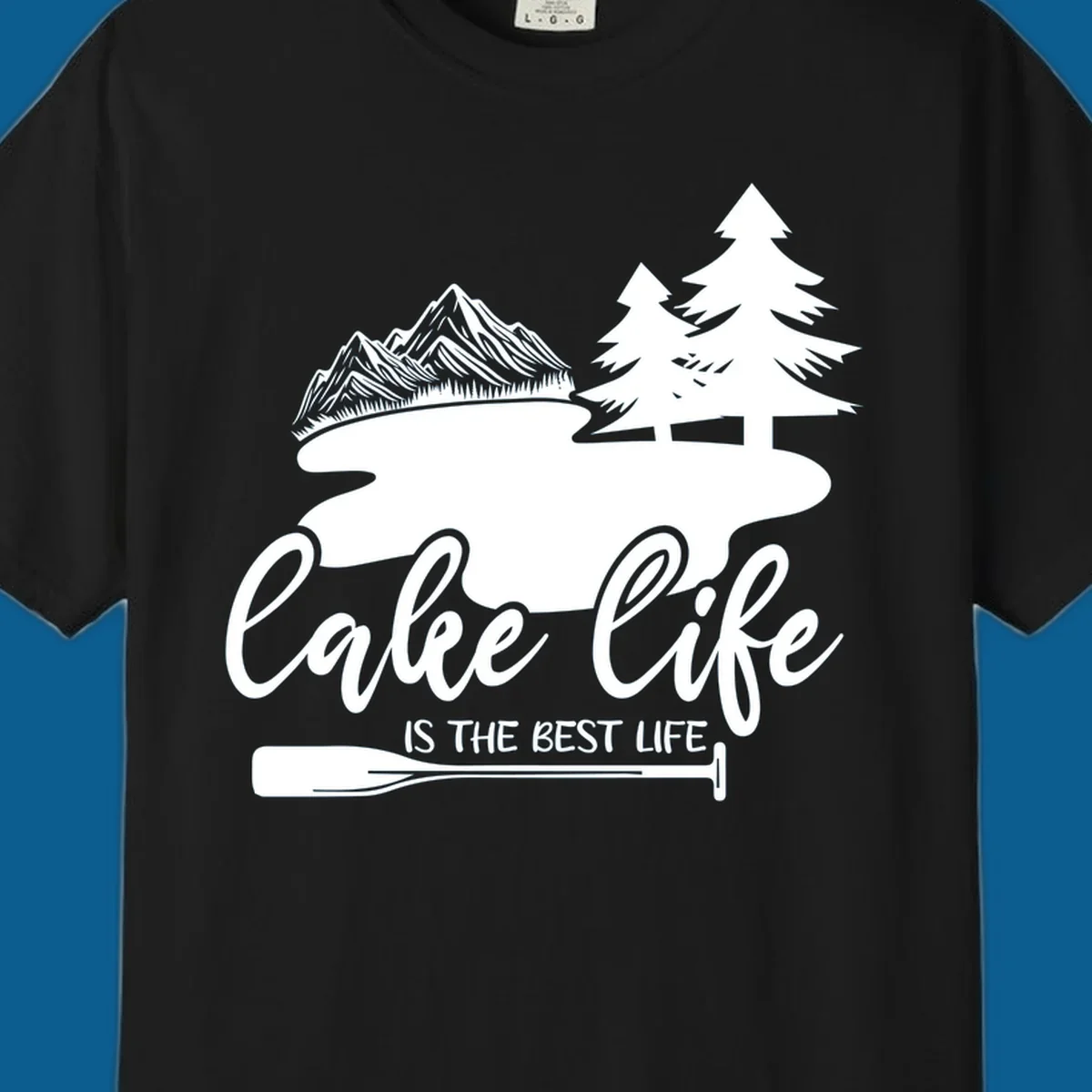 Lake life is the best life design with mountains, trees, lake, and paddle graphic.