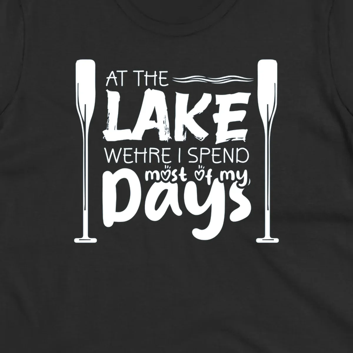 Text design "At The Lake Where I Spend Most Of My Days" with paddles and waves, lake-life-days concept.