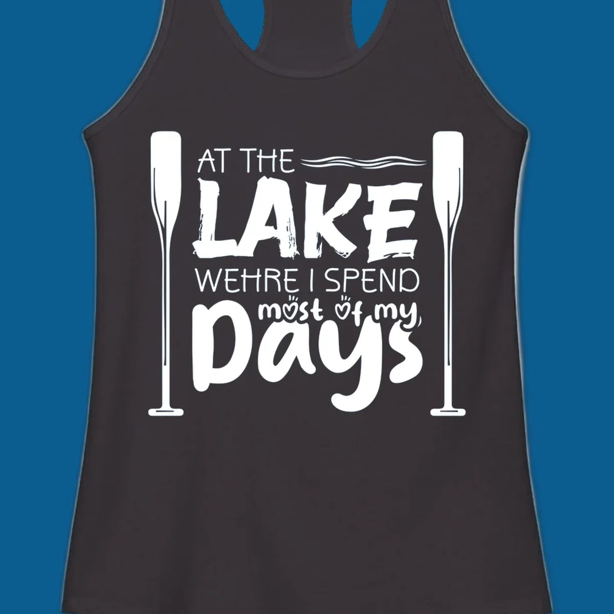 Text design "At The Lake Where I Spend Most Of My Days" with paddles and waves, lake-life-days concept.