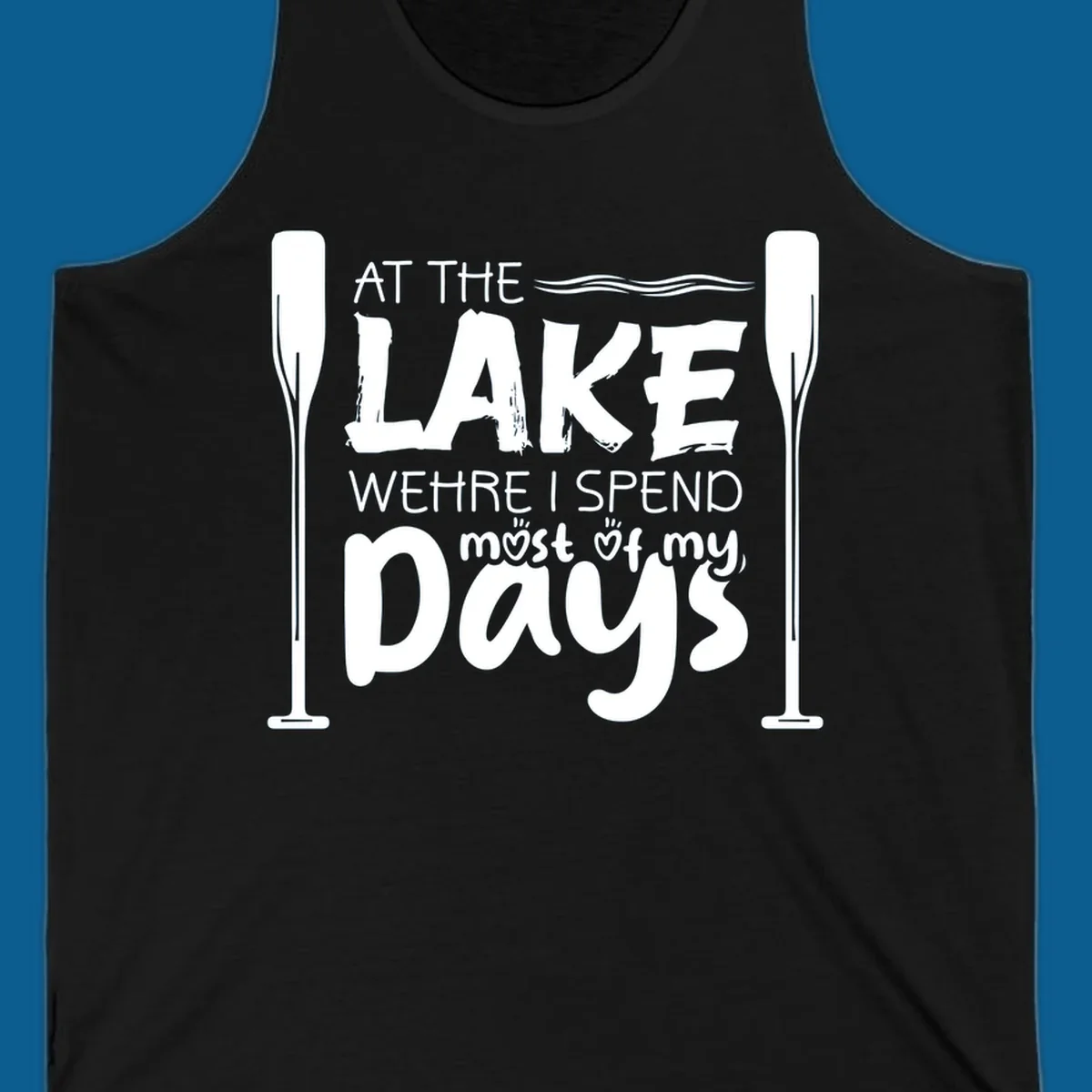 Text design "At The Lake Where I Spend Most Of My Days" with paddles and waves, lake-life-days concept.