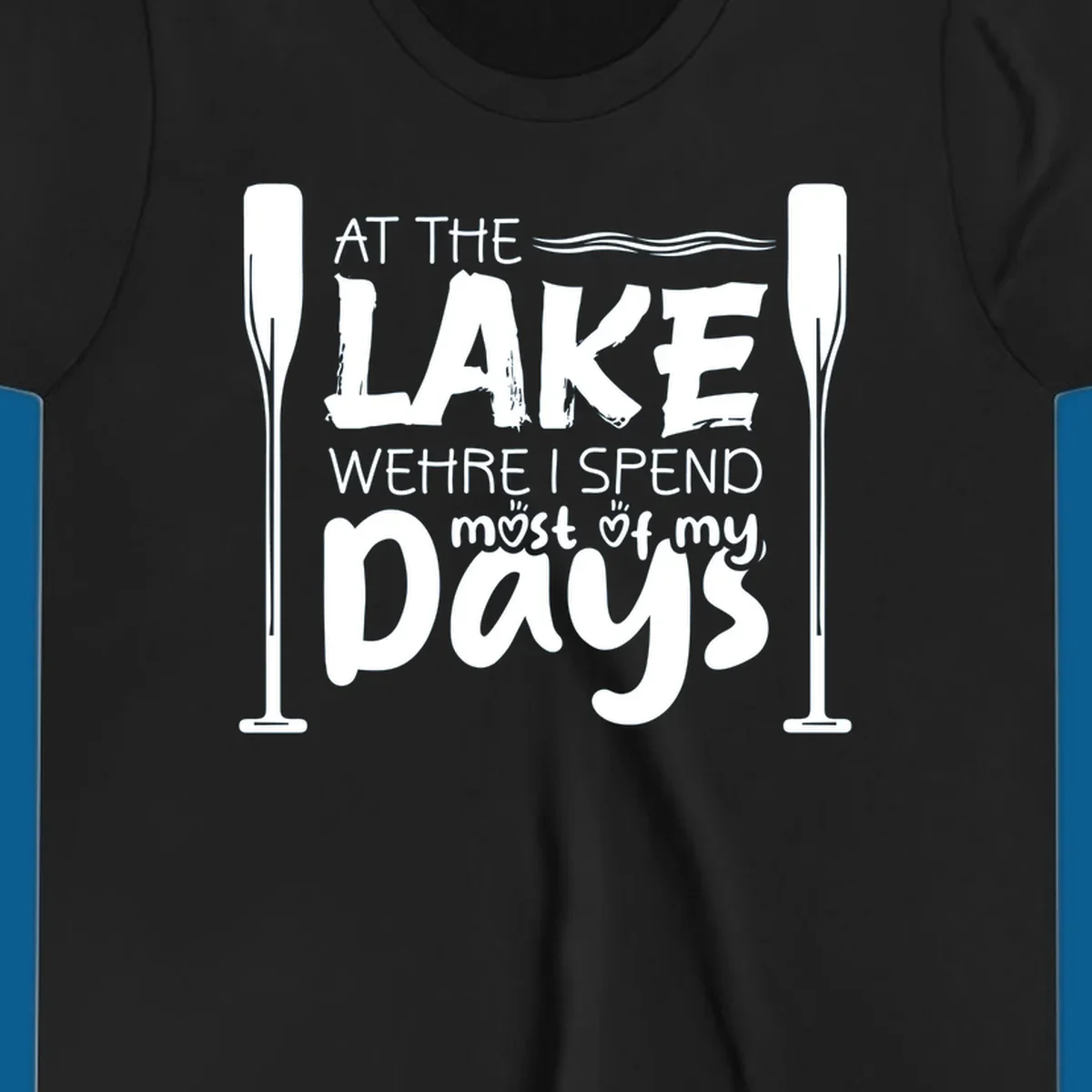 Text design "At The Lake Where I Spend Most Of My Days" with paddles and waves, lake-life-days concept.