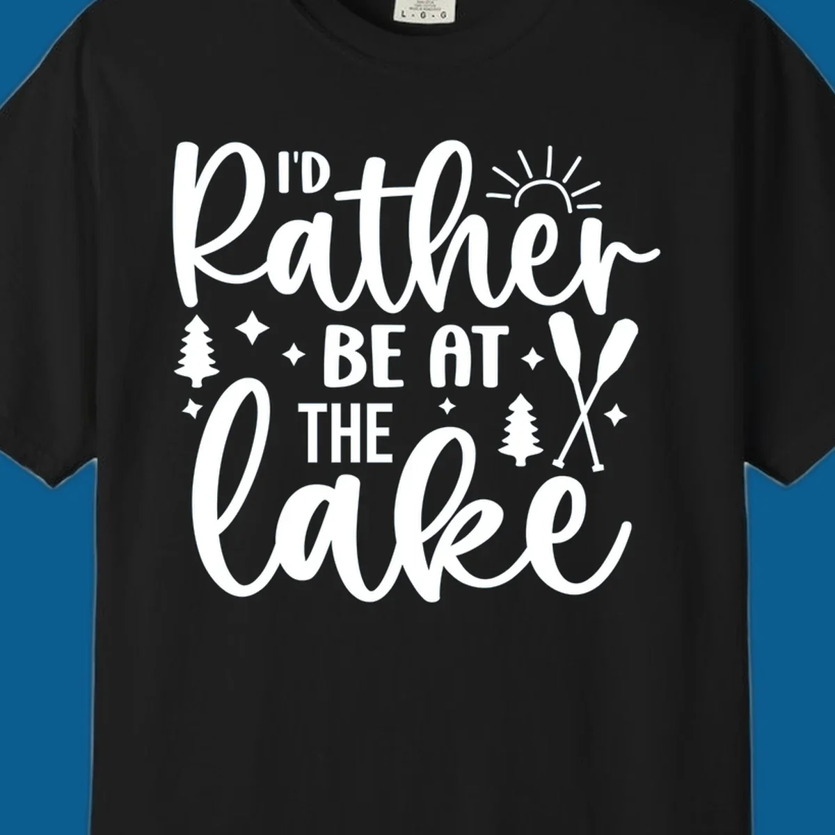 I'd Rather Be At The Lake typography design with sun rays, trees, and oars.