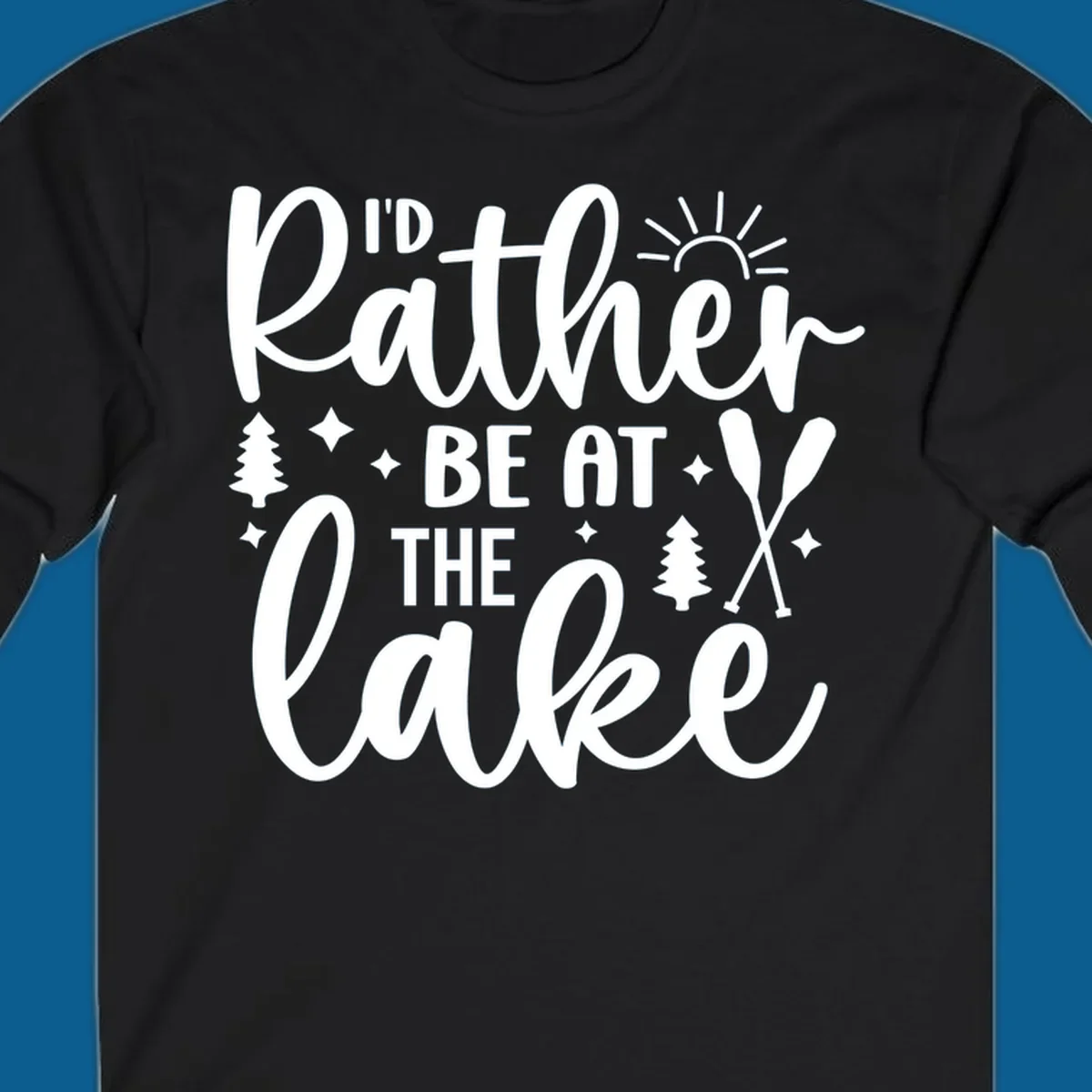 I'd Rather Be At The Lake typography design with sun rays, trees, and oars.