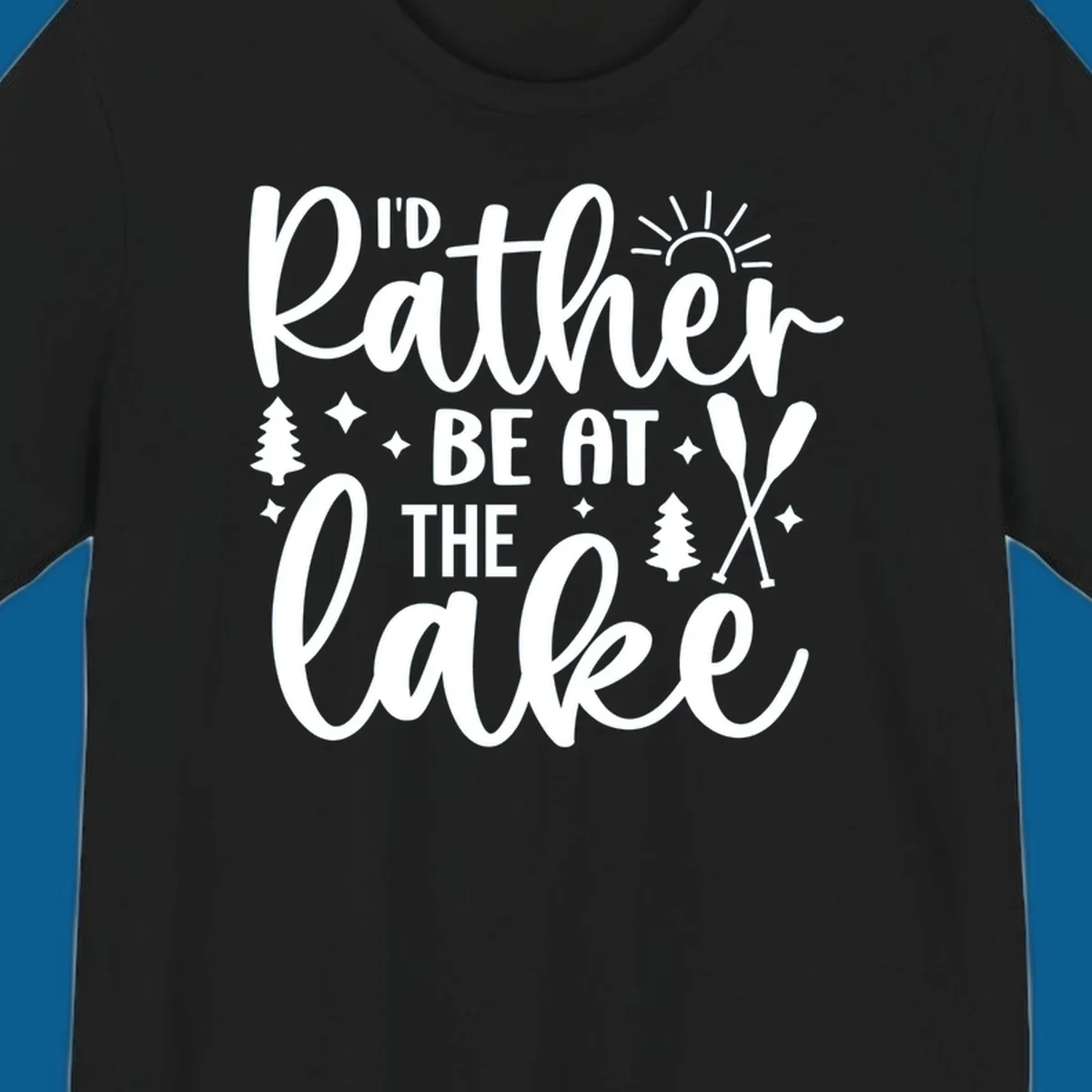 I'd Rather Be At The Lake typography design with sun rays, trees, and oars.