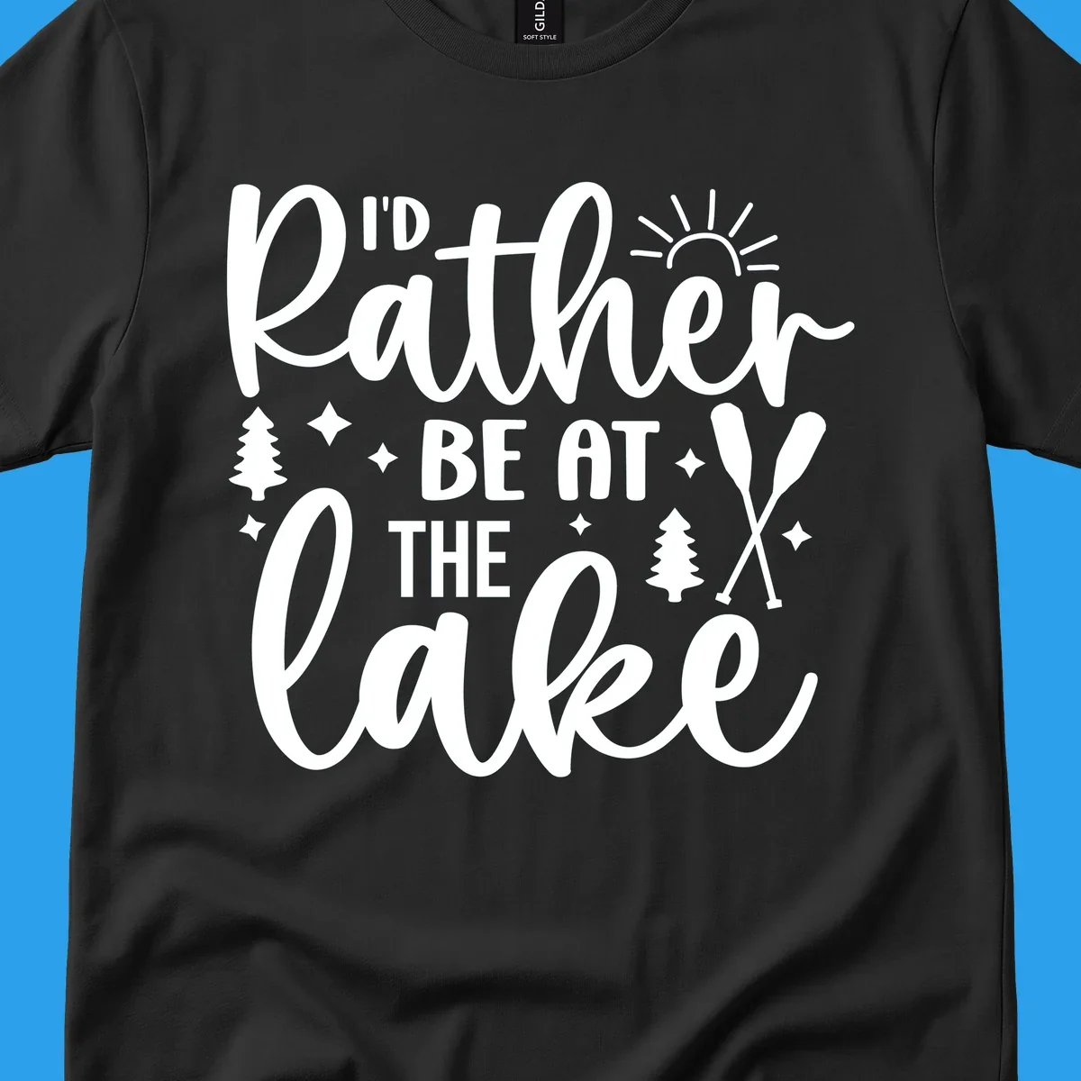 I'd Rather Be At The Lake typography design with sun rays, trees, and oars.