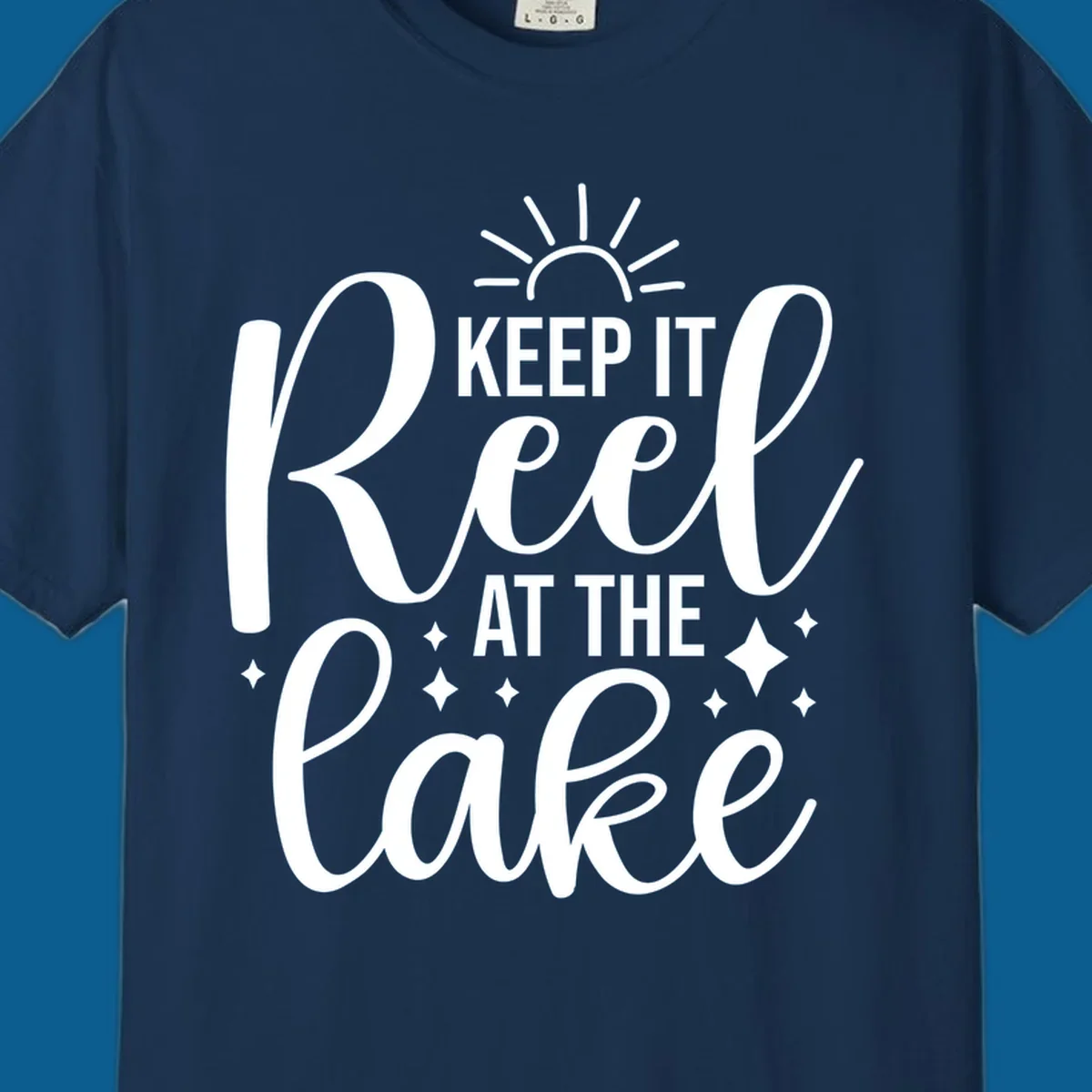 Keep It Reel At The Lake design with sun rays and sparkles, a lakeside lifestyle graphic.