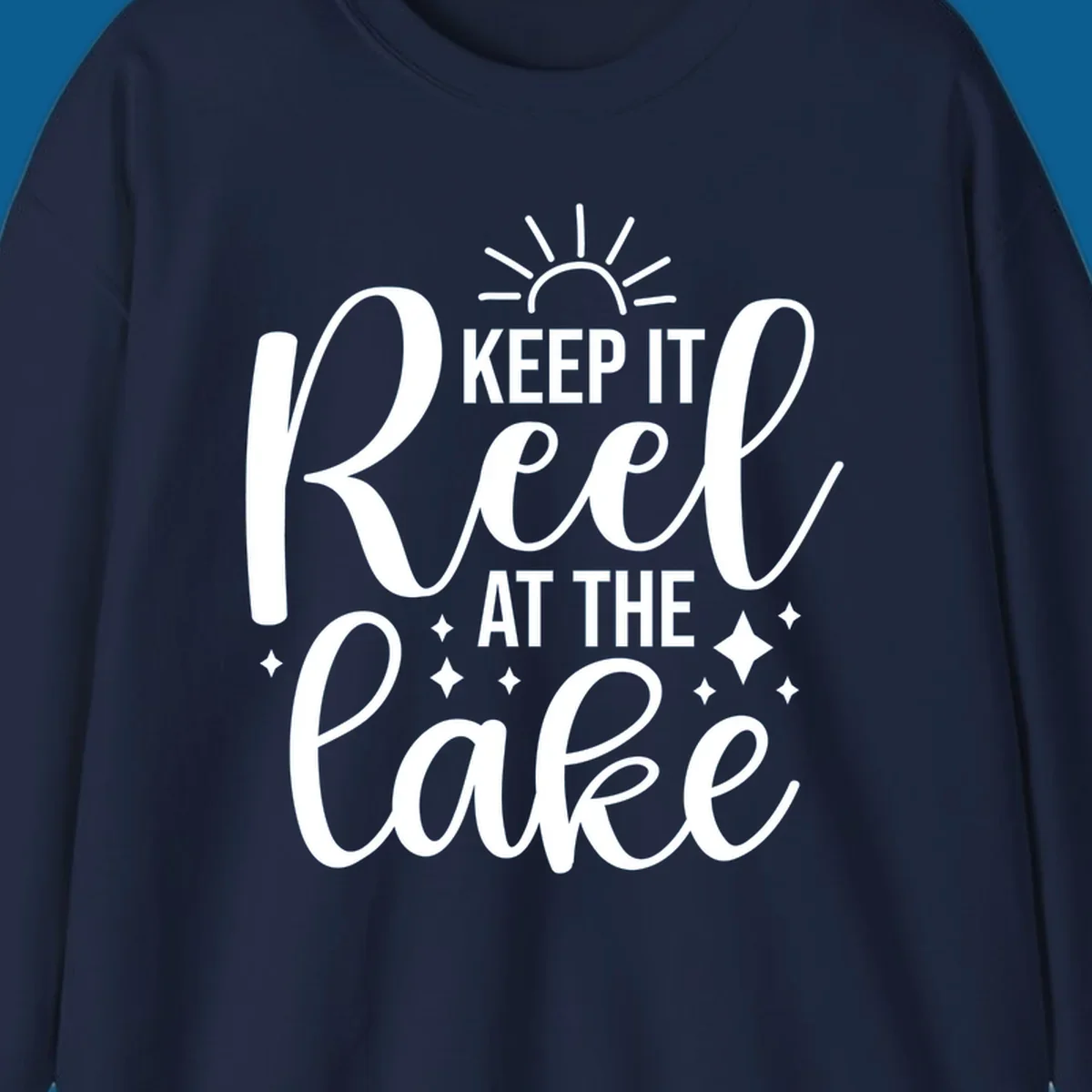 Keep It Reel At The Lake design with sun rays and sparkles, a lakeside lifestyle graphic.