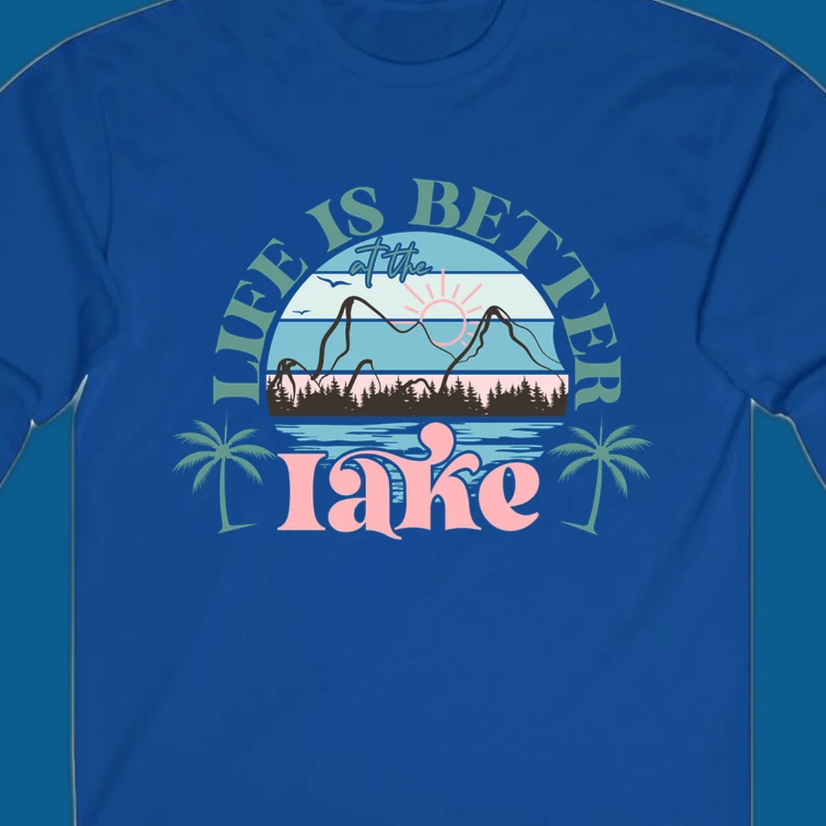 Life is better at the lake scenic design with mountains, trees, lake, and palm trees.