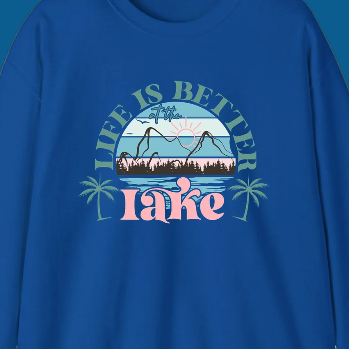 Life is better at the lake scenic design with mountains, trees, lake, and palm trees.