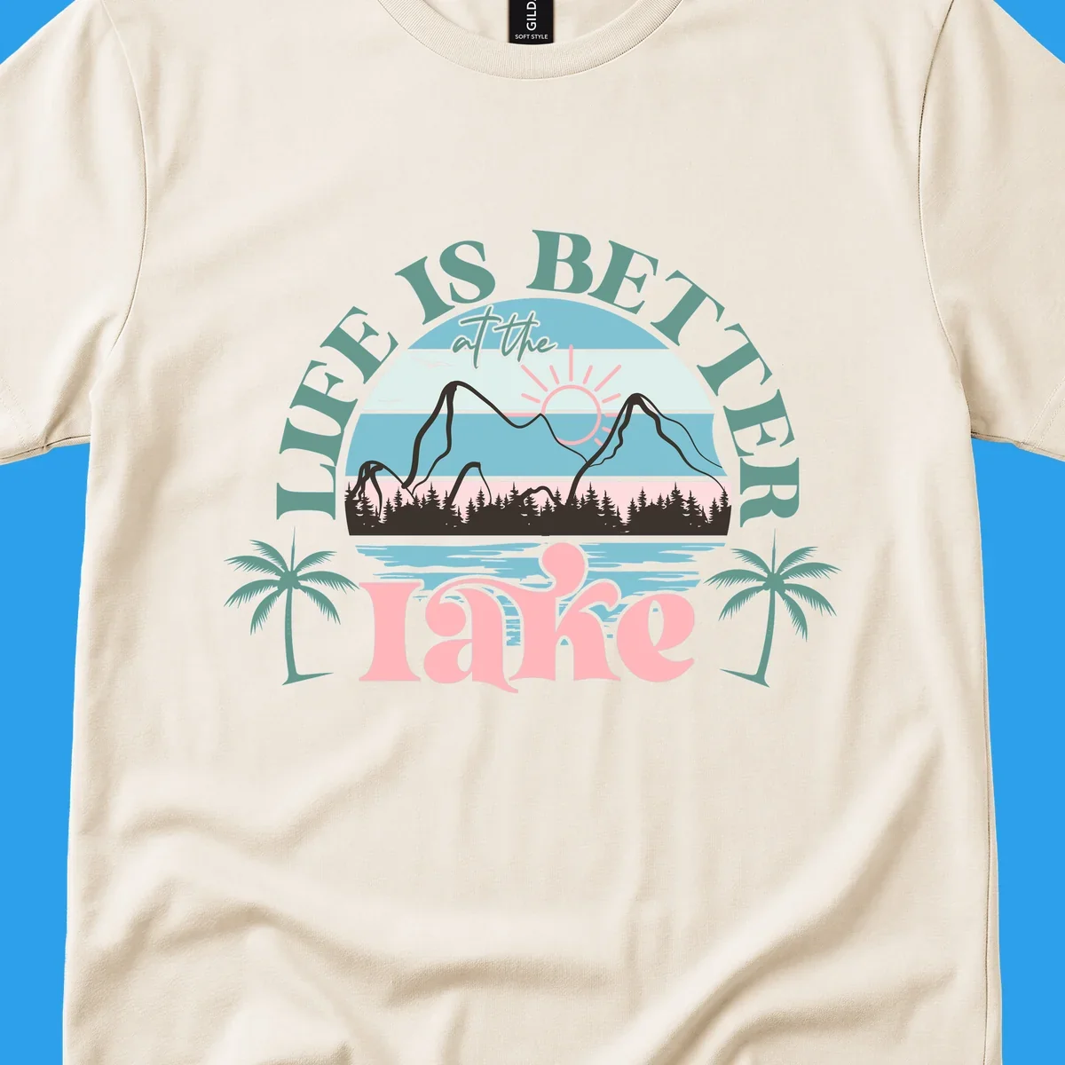 Life is better at the lake scenic design with mountains, trees, lake, and palm trees.