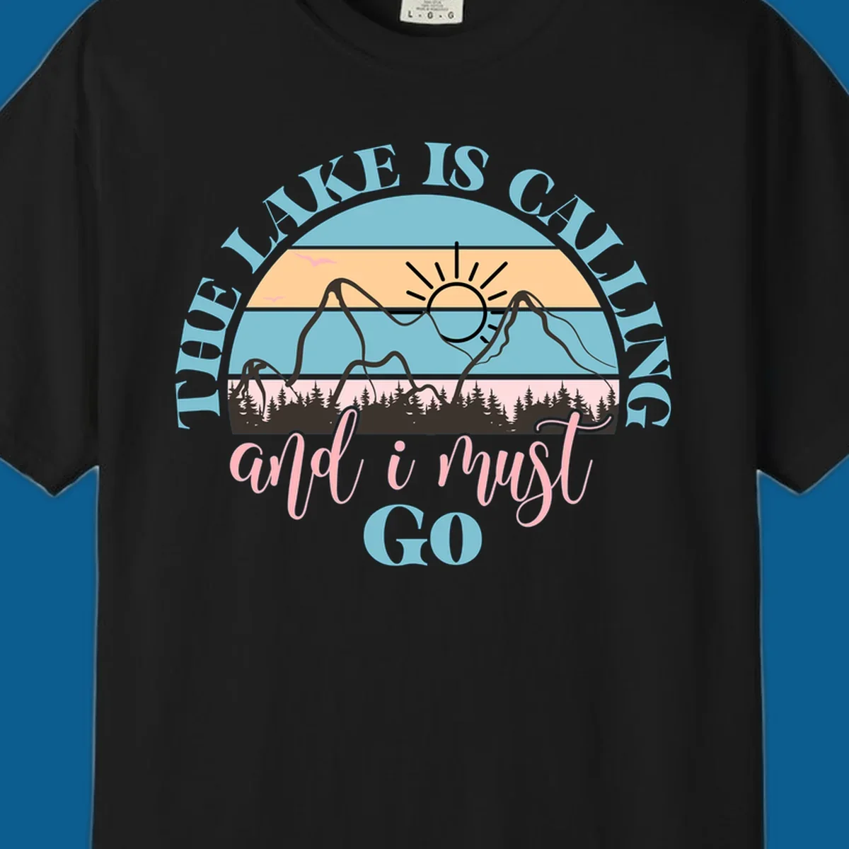 The Lake Is Calling And I Must Go text with mountain and sunset illustration.