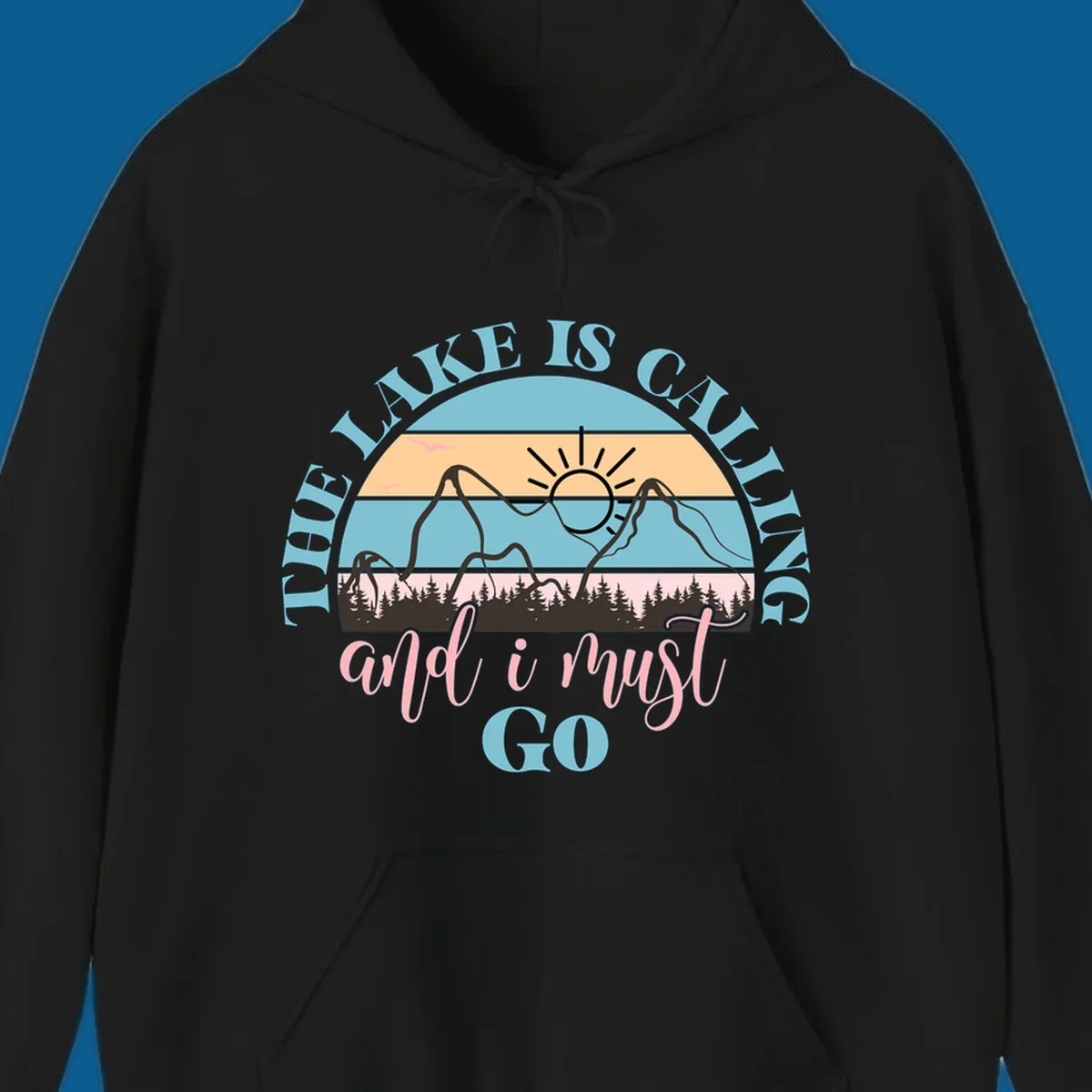 The Lake Is Calling And I Must Go text with mountain and sunset illustration.