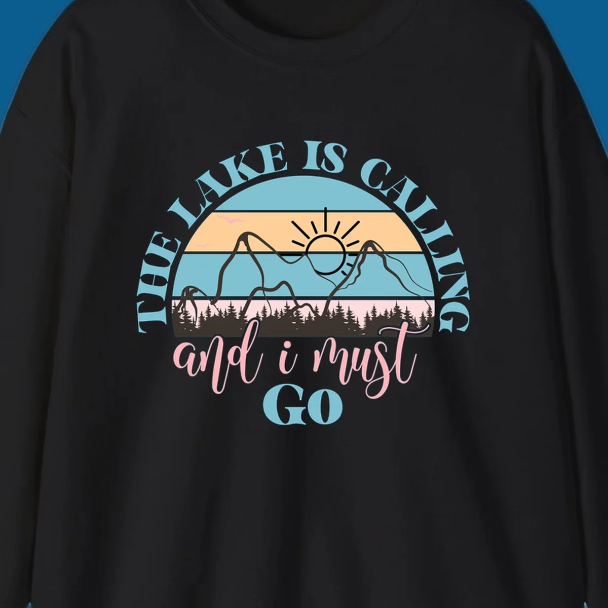 The Lake Is Calling And I Must Go text with mountain and sunset illustration.