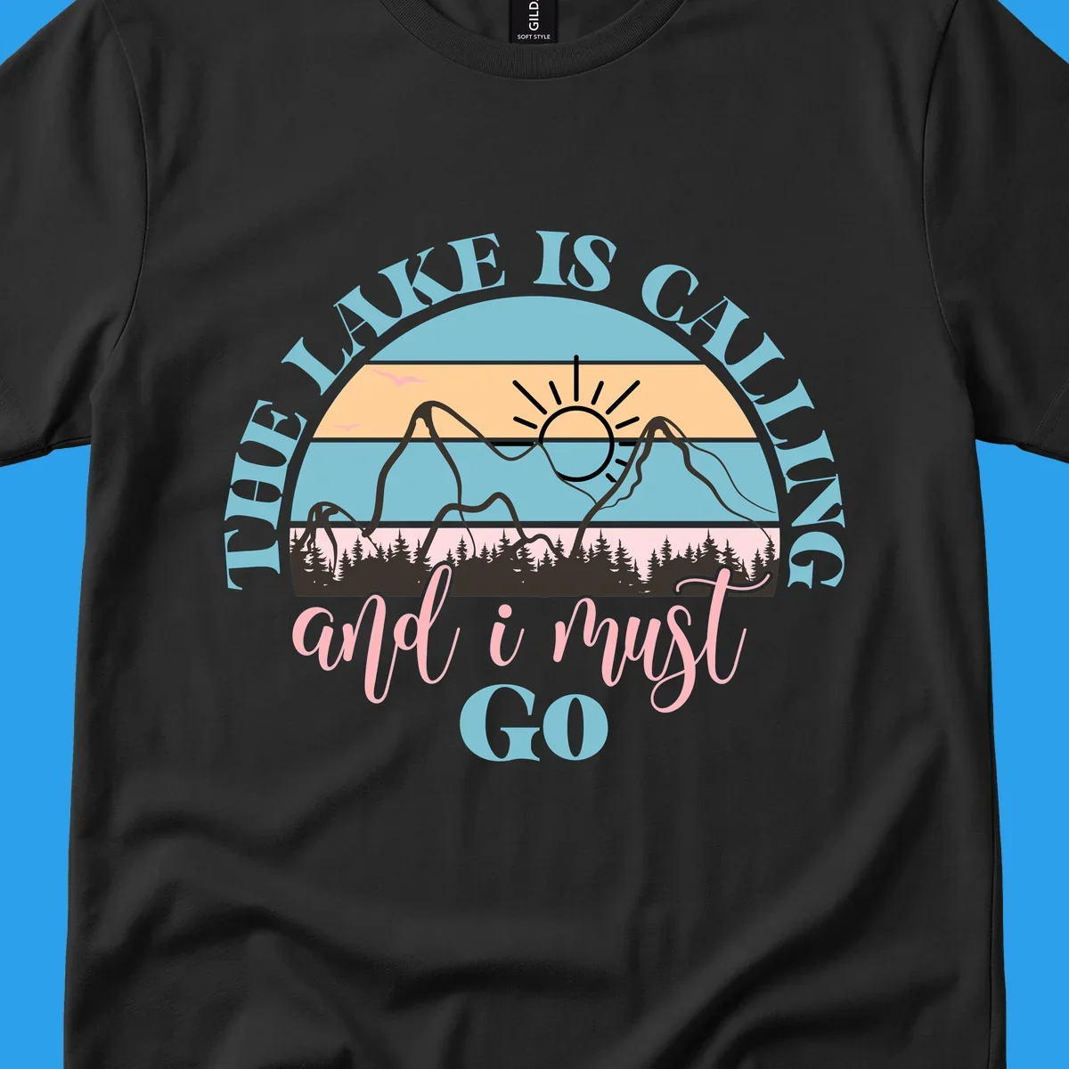 The Lake Is Calling And I Must Go text with mountain and sunset illustration.