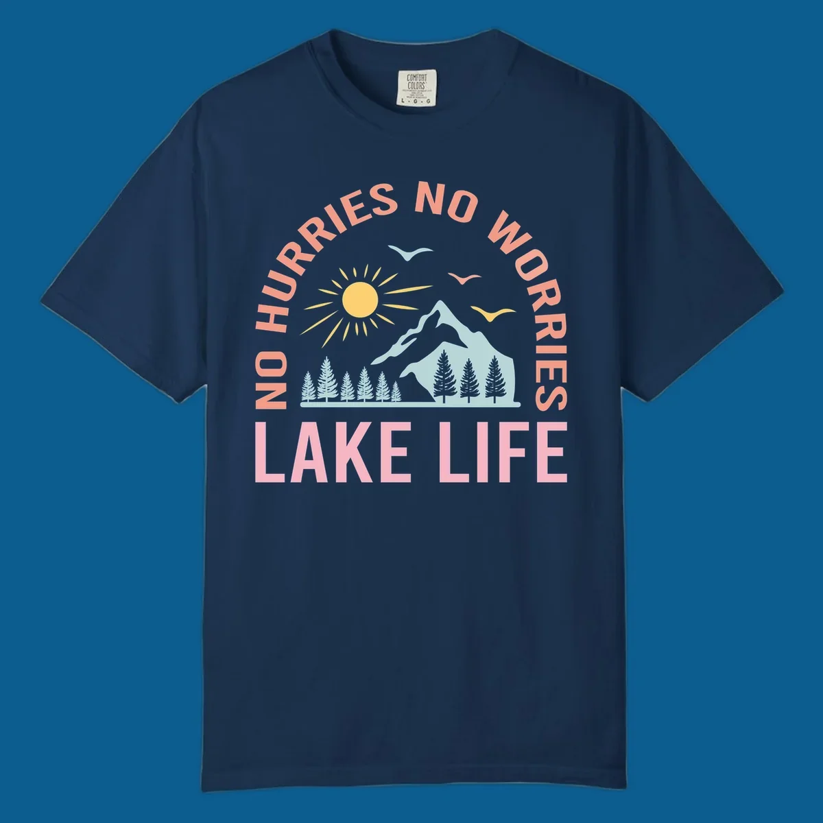 Lake life scenic design with mountains, sun, trees, and no worries text.