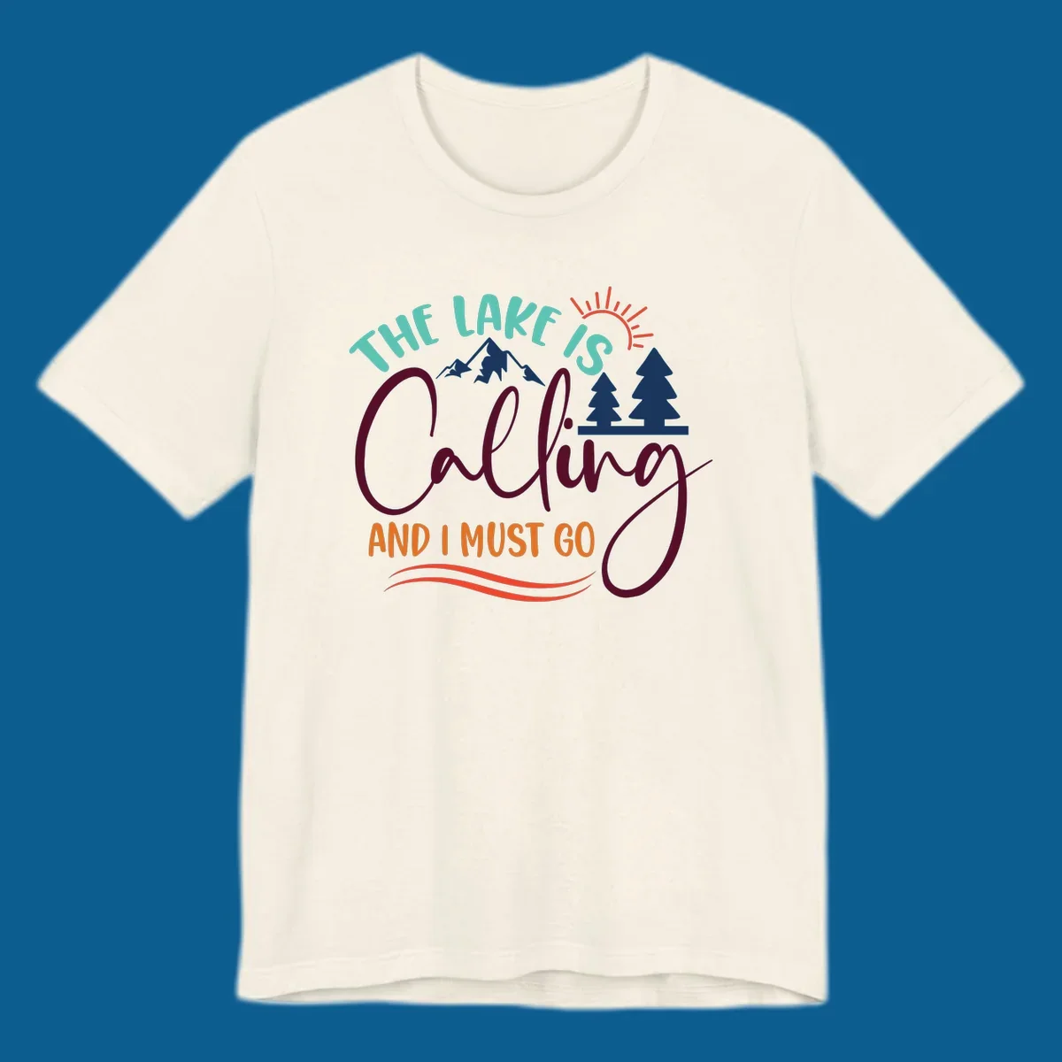 The Lake Is Calling And I Must Go nature graphic with mountains, trees, and sun rays.