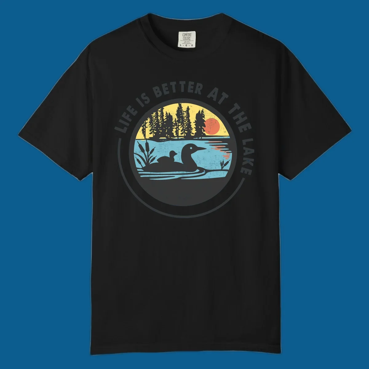 Circular lake scene with loons and trees, text "Life Is Better At The Lake".