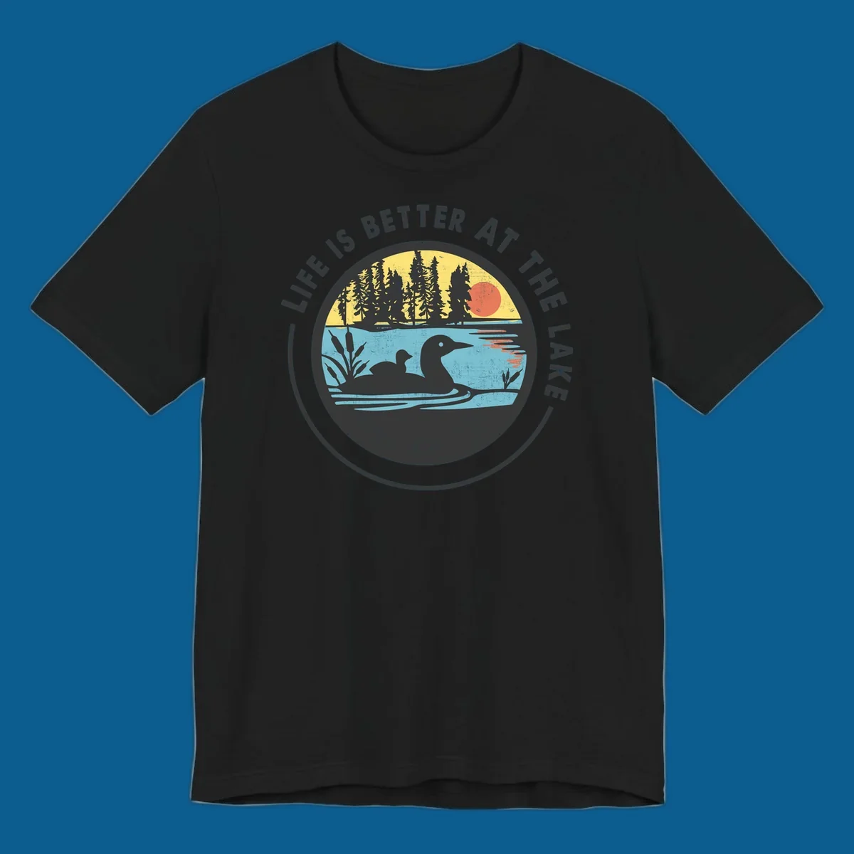 Circular lake scene with loons and trees, text "Life Is Better At The Lake".