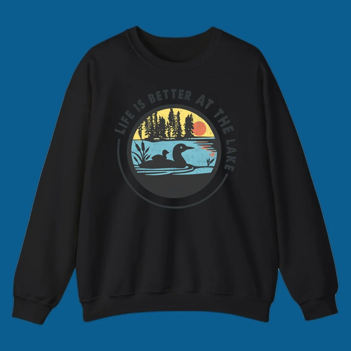 Circular lake scene with loons and trees, text "Life Is Better At The Lake".