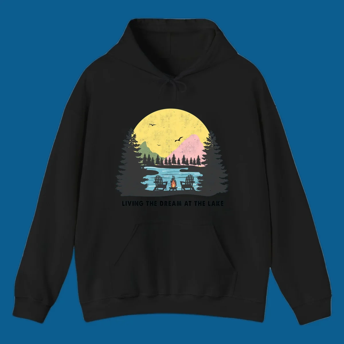 Lake life dream scene with Adirondack chairs, campfire, and sunset over mountains. Text: LIVING THE DREAM AT THE LAKE