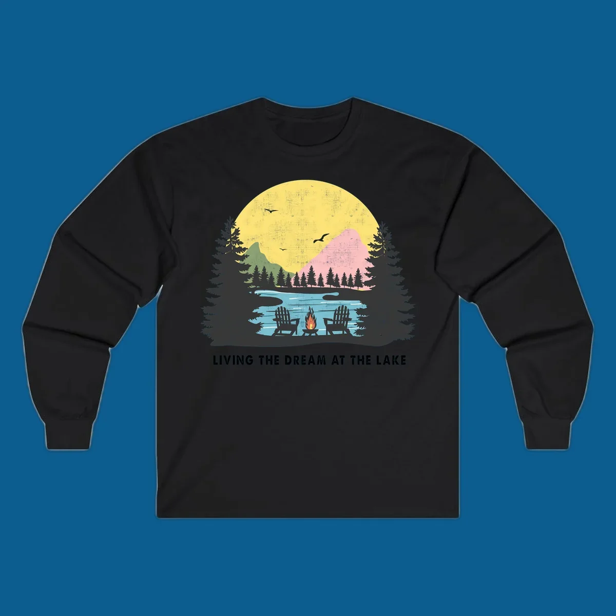 Lake life dream scene with Adirondack chairs, campfire, and sunset over mountains. Text: LIVING THE DREAM AT THE LAKE