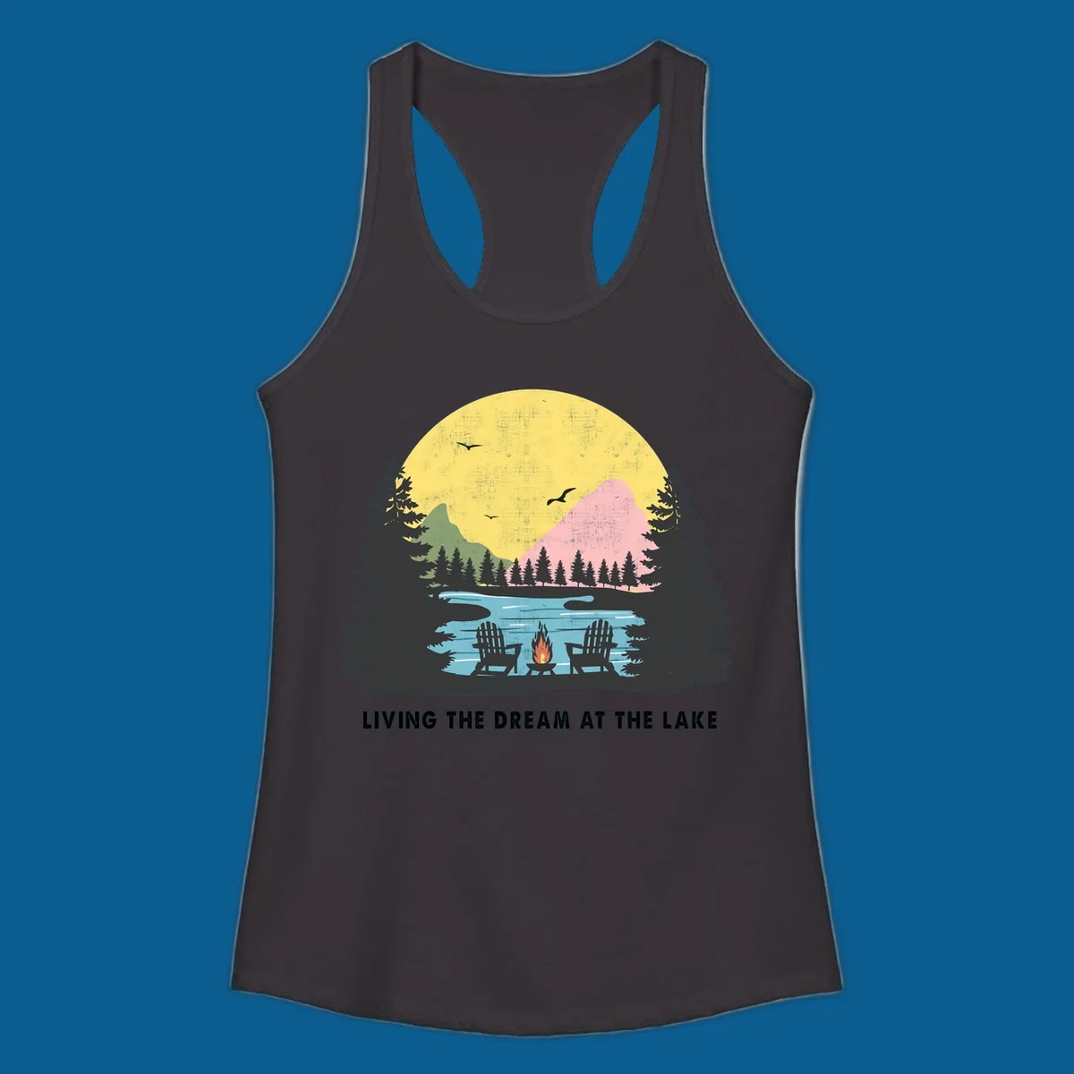 Lake life dream scene with Adirondack chairs, campfire, and sunset over mountains. Text: LIVING THE DREAM AT THE LAKE