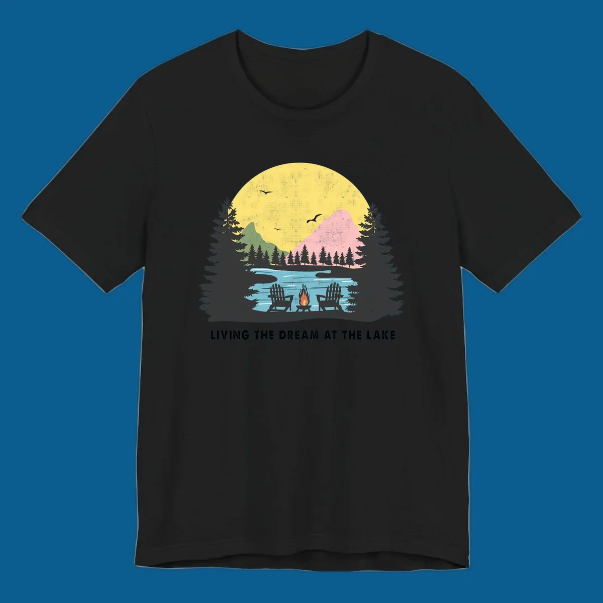 Lake life dream scene with Adirondack chairs, campfire, and sunset over mountains. Text: LIVING THE DREAM AT THE LAKE