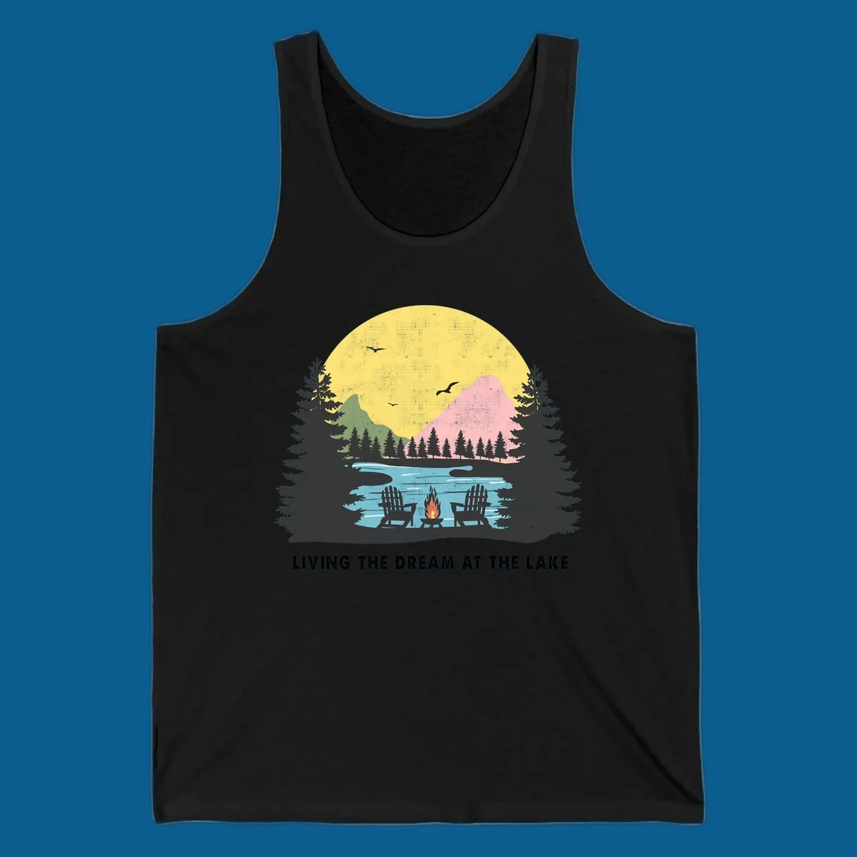 Lake life dream scene with Adirondack chairs, campfire, and sunset over mountains. Text: LIVING THE DREAM AT THE LAKE