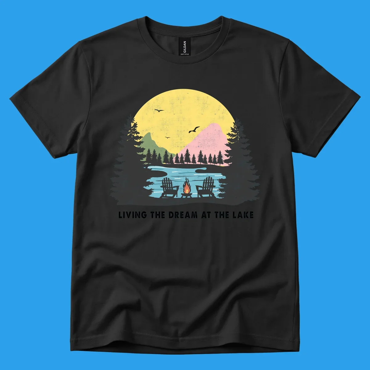 Lake life dream scene with Adirondack chairs, campfire, and sunset over mountains. Text: LIVING THE DREAM AT THE LAKE