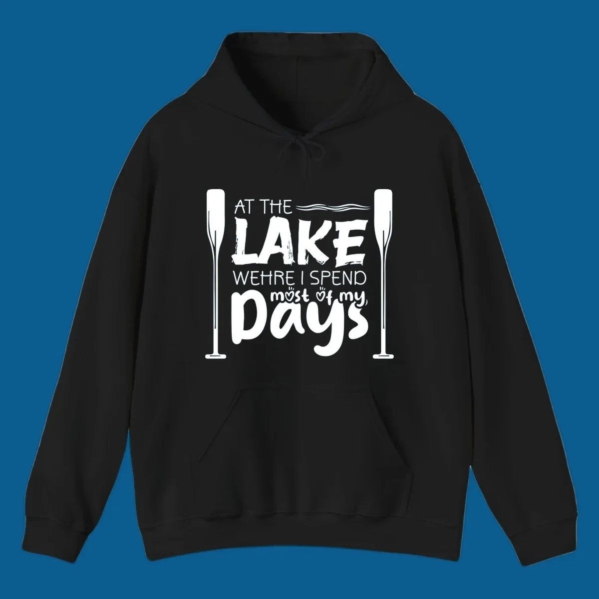Text design "At The Lake Where I Spend Most Of My Days" with paddles and waves, lake-life-days concept.