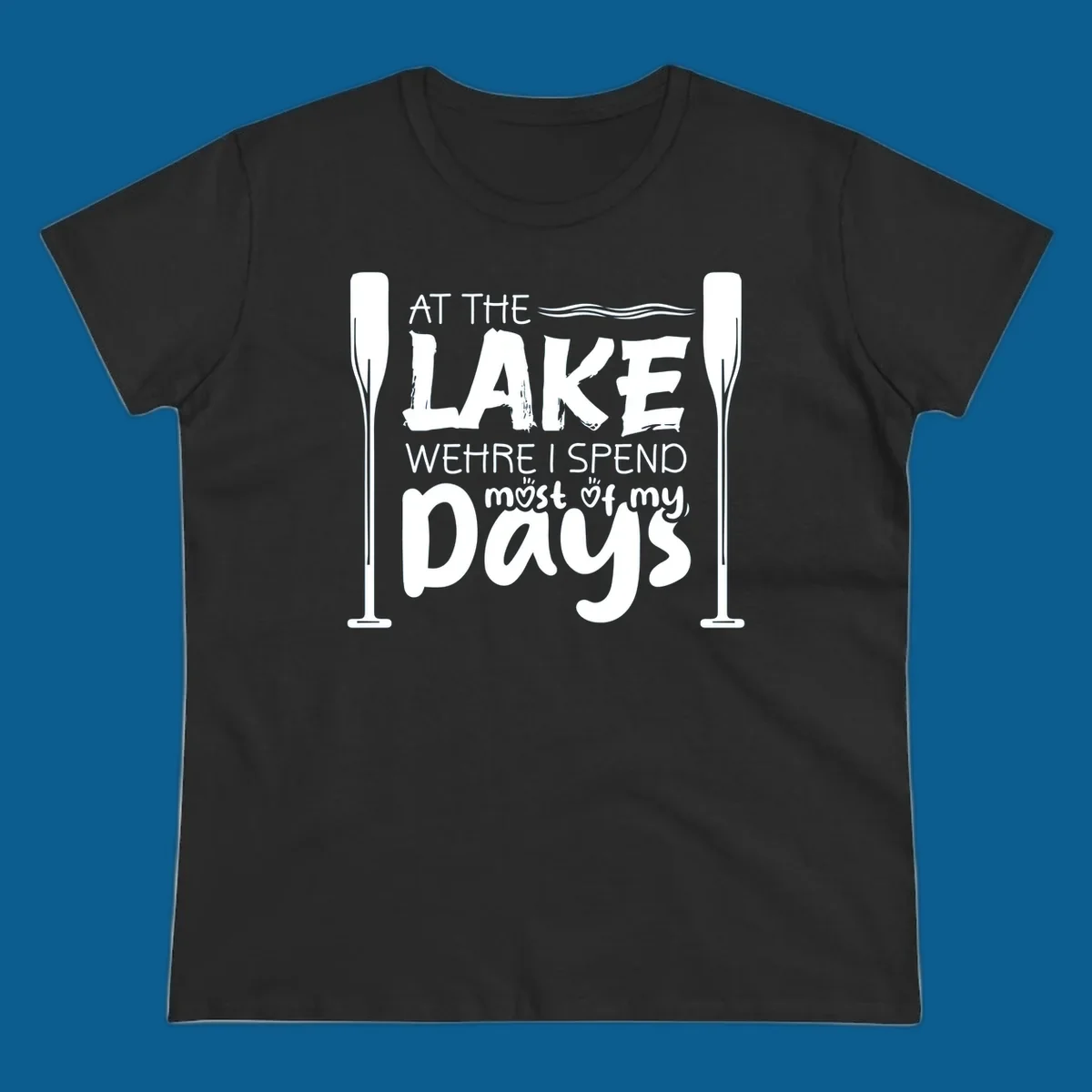 Text design "At The Lake Where I Spend Most Of My Days" with paddles and waves, lake-life-days concept.