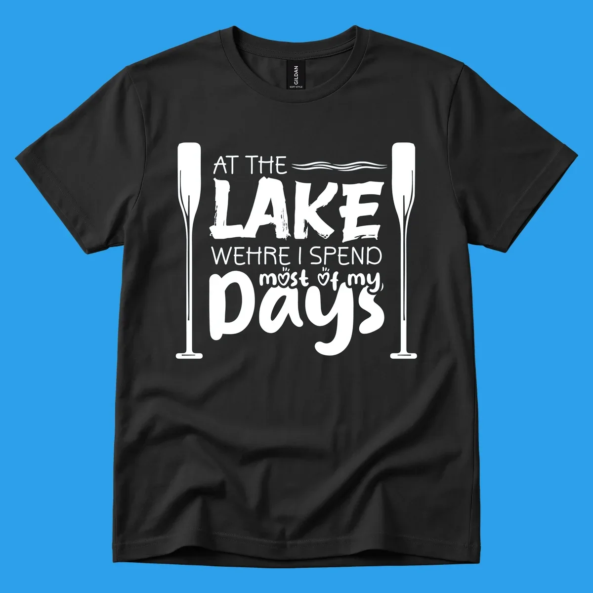 Text design "At The Lake Where I Spend Most Of My Days" with paddles and waves, lake-life-days concept.