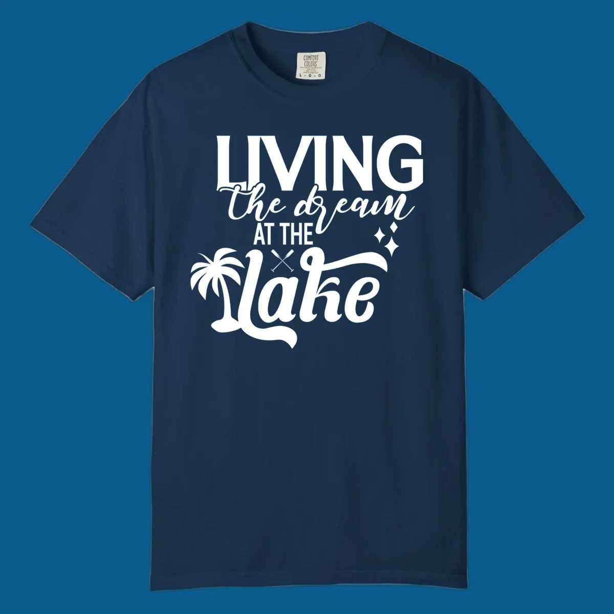 Living the dream at the lake text with palm tree and oars graphic