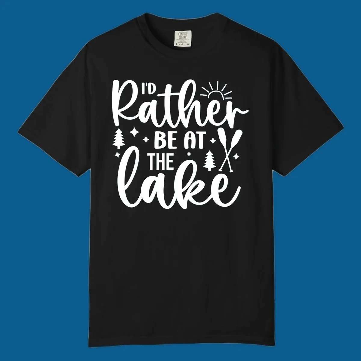 I'd Rather Be At The Lake typography design with sun rays, trees, and oars.