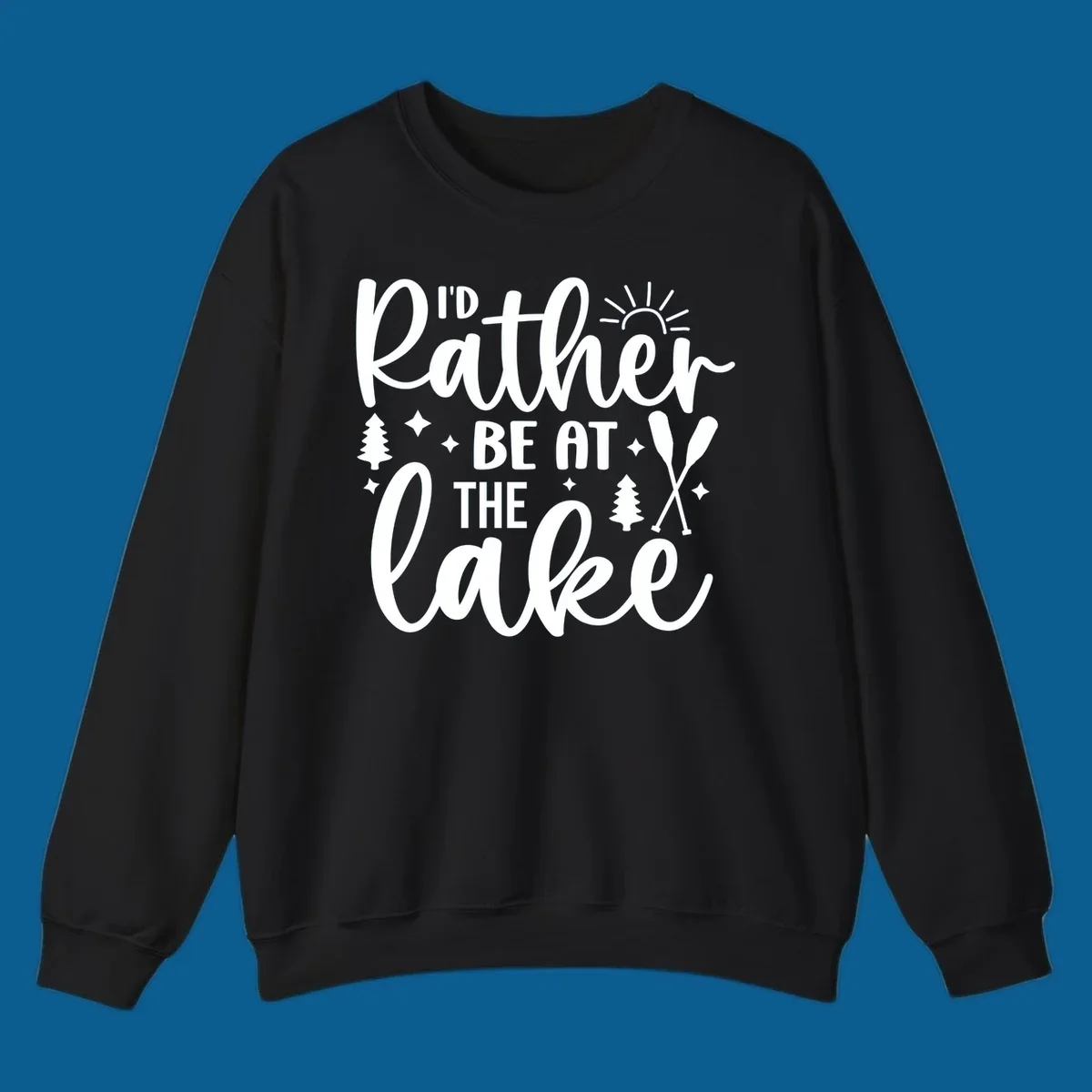 I'd Rather Be At The Lake typography design with sun rays, trees, and oars.