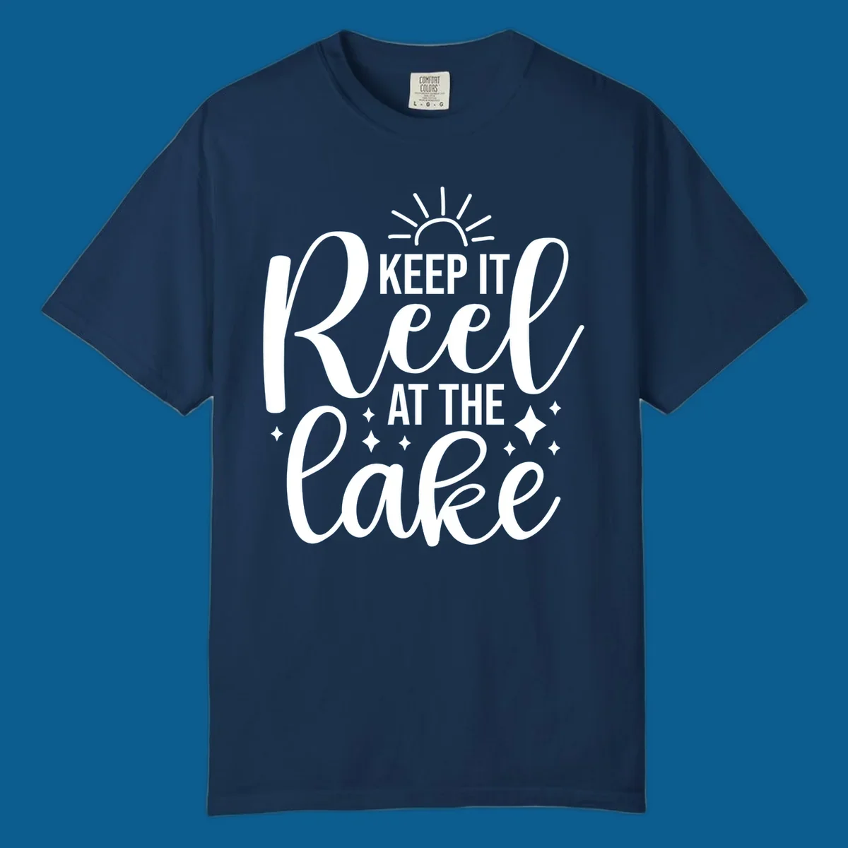 Keep It Reel At The Lake design with sun rays and sparkles, a lakeside lifestyle graphic.