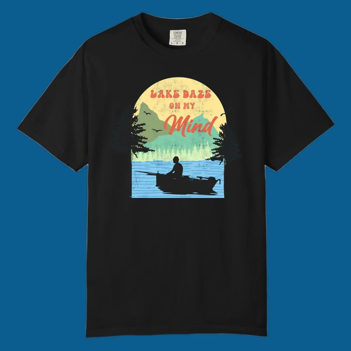 Lake daze fishing design featuring a person in a boat on a lake with trees and mountains.