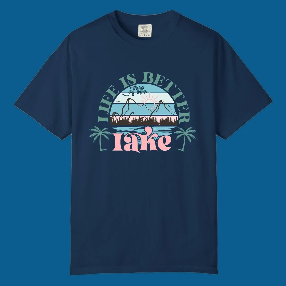 Life is better at the lake scenic design with mountains, trees, lake, and palm trees.