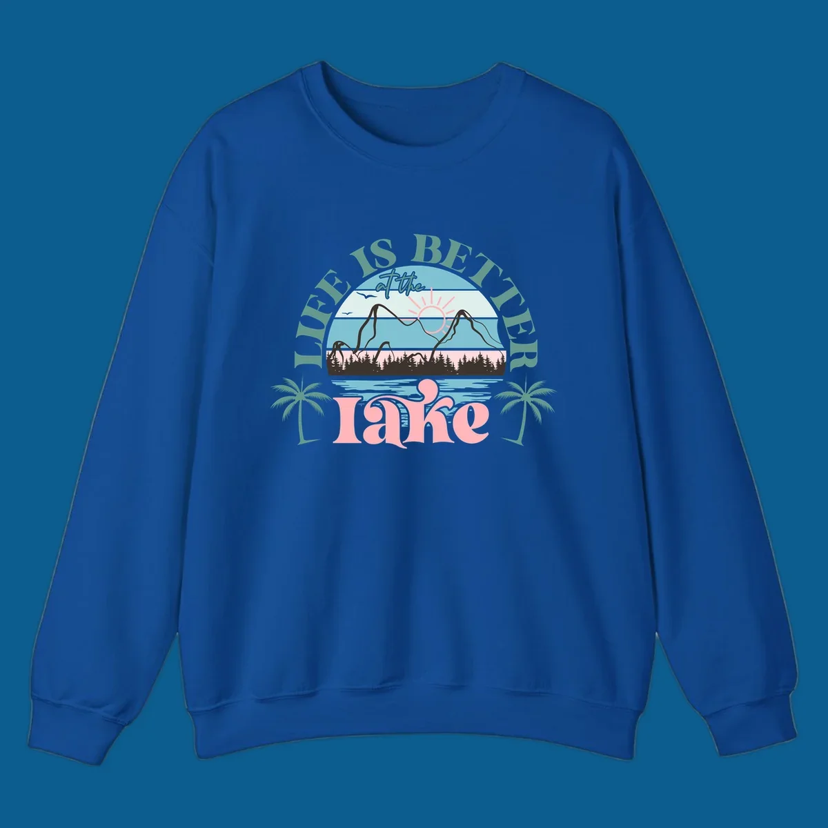 Life is better at the lake scenic design with mountains, trees, lake, and palm trees.