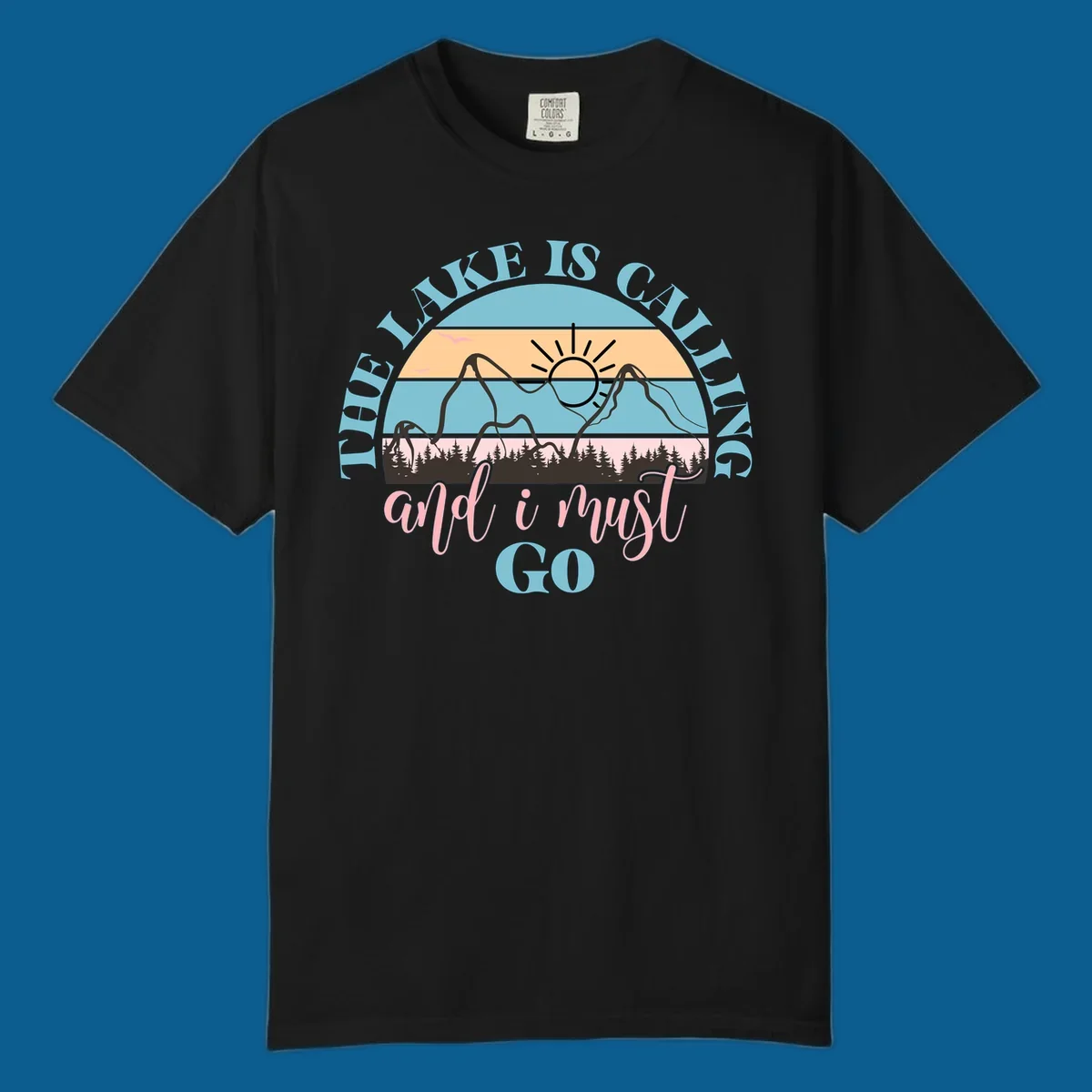 The Lake Is Calling And I Must Go text with mountain and sunset illustration.