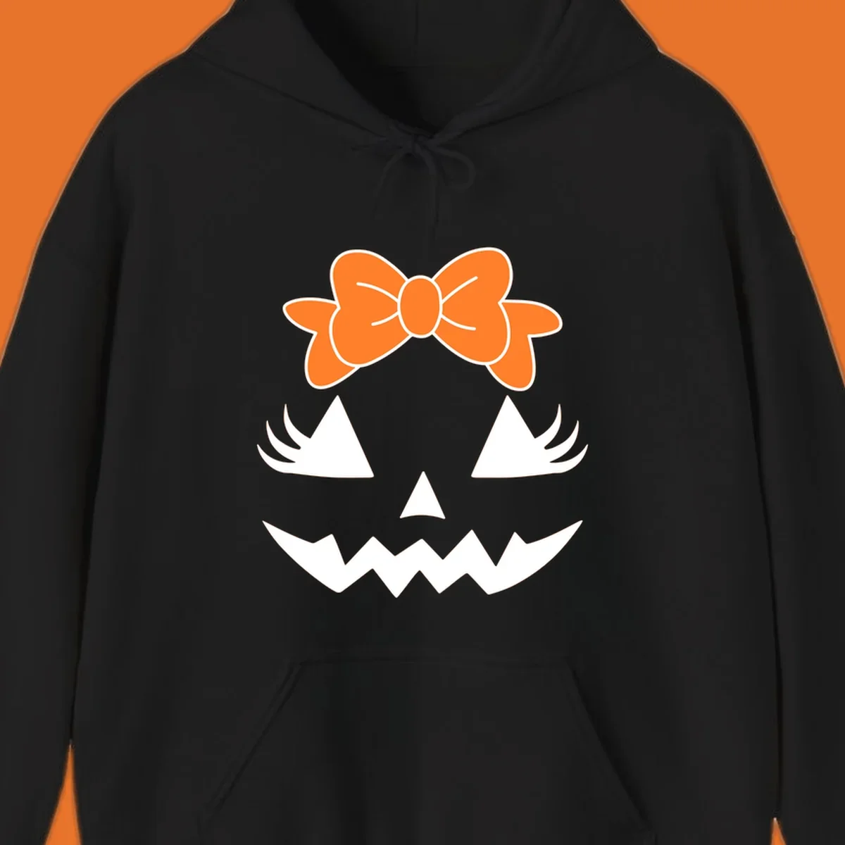 Cute pumpkin face graphic with orange bow, triangle eyes, nose, and jagged smile.