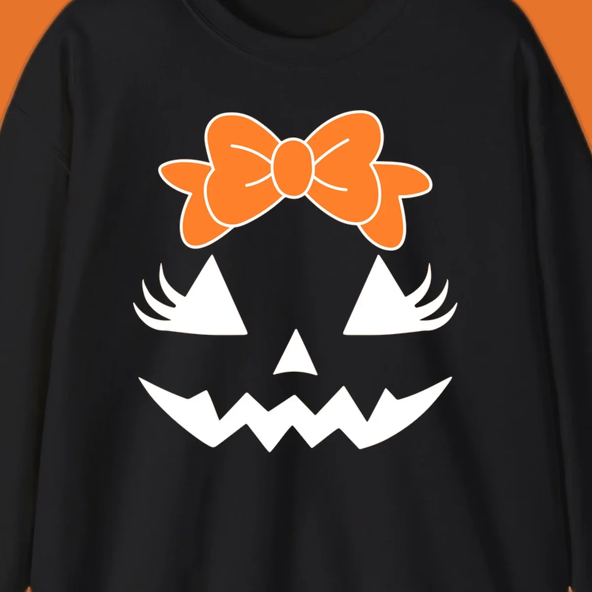 Cute pumpkin face graphic with orange bow, triangle eyes, nose, and jagged smile.