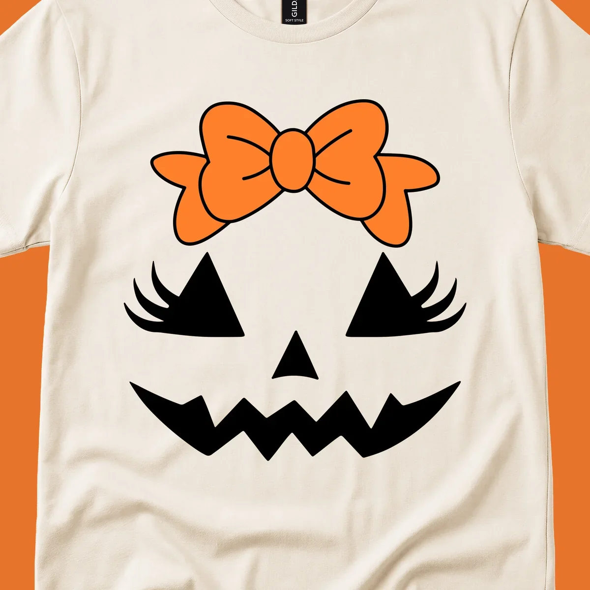 Cute pumpkin face graphic with orange bow, triangle eyes, nose, and jagged smile.